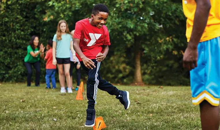 child wearing a YMCA t-shirt playing an outdoor game