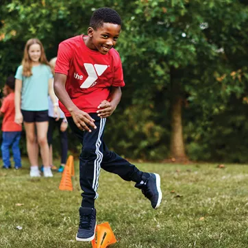 child wearing a YMCA t-shirt playing an outdoor game