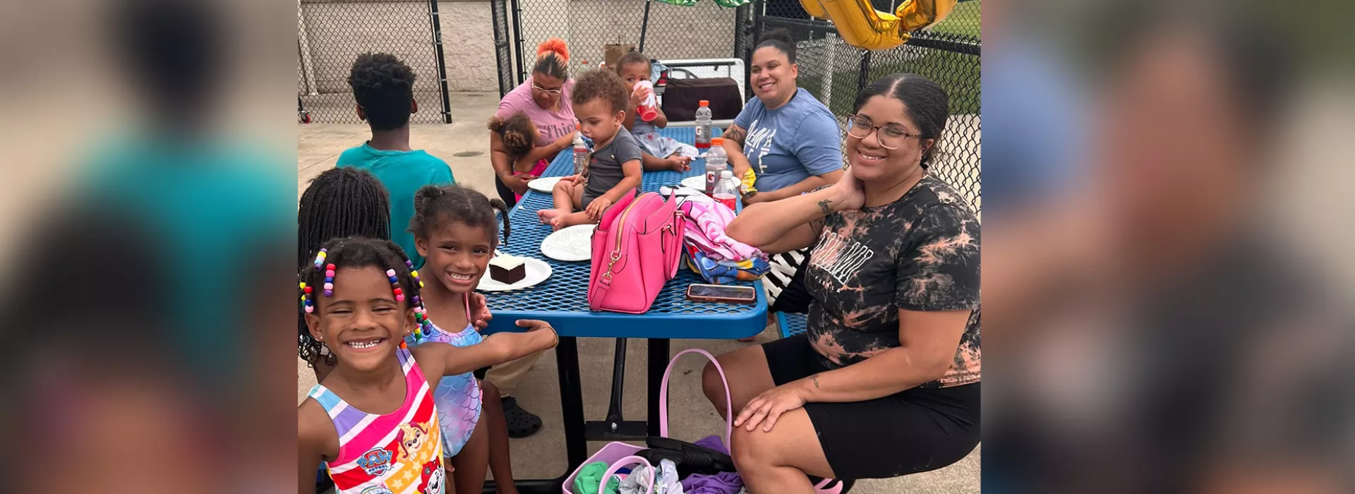 children and adults smiling at a picnic table outside